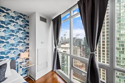 a bedroom with a large window with a view of the city at Chic Fort York Studio Cozy Retreat in Downtown in Toronto