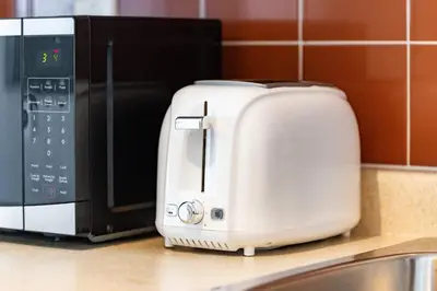 a white toaster sitting next to a microwave on a counter at Chic Fort York Studio Cozy Retreat in Downtown in Toronto