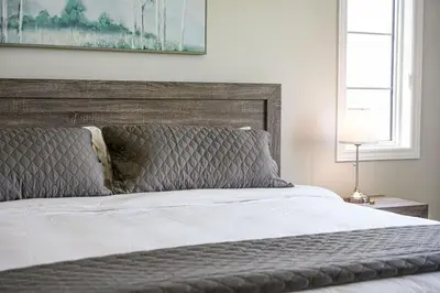 a bedroom with a large bed with a wooden headboard at Spacious 3BR Townhome Near Casino & Thermea Spa in Ajax