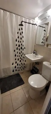 a bathroom with a shower curtain with a toilet and a sink at Medium size room for 2 in Toronto