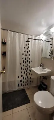a bathroom with a shower curtain with a toilet and a sink at Medium size room for 2 in Toronto