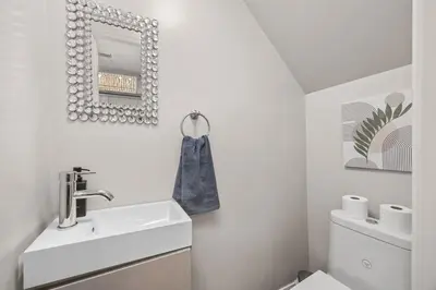 a white bathroom with a sink and a mirror at Entire Unit - Steps From History - 5 Mins To Beaches in Toronto