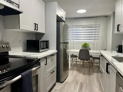a kitchen with white cabinets and a table with a microwave at Modern 2 bedroom, 2 king beds, close to Hwy in Kitchener