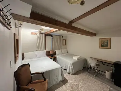 a bedroom with two beds and a desk and a tv at Carlton House in Toronto