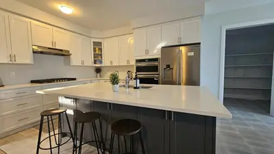 a kitchen with white cabinets and a island with bar stools at Grand Woodstock Luxe House 4BR in Woodstock