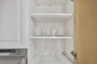 a kitchen with two wine glasses in a cabinet at Chic and Bright 1BR Apt with Free Wifi and Parking in Whitby