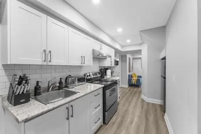 a kitchen with white cabinets and a sink at Modern 2-Bed, 2-Bath BSMT suite with Pvt Entrance Free Parking and Wi Fi in Pickering