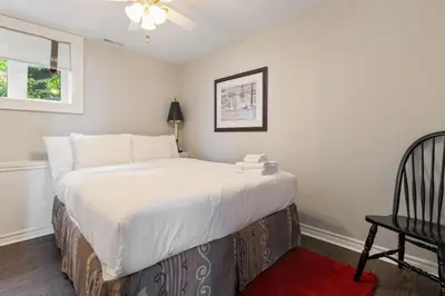 a bedroom with a large bed and a chair at Serene Waterfront Escape On Private Lane in Thornbury