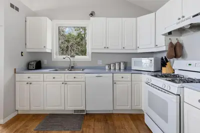 a white kitchen with white appliances and a window at Serene Waterfront Escape On Private Lane in Thornbury