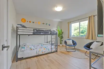 a bedroom with a bunk bed and a chair at Niagara Retreat|HotTub|Sauna|Games|15 Min to Falls in Thorold