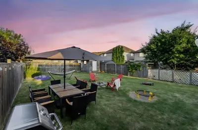 a backyard with a table and chairs and an umbrella at Niagara Retreat|HotTub|Sauna|Games|15 Min to Falls in Thorold