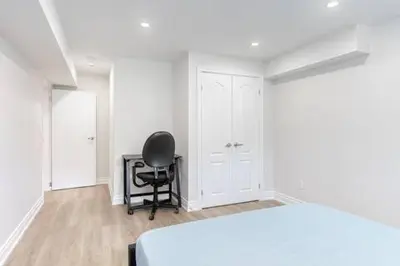 a bedroom with a black chair and a white bed at Cozy 3BR 2 Bath Lower Level Close to Shops in Richmond Hill