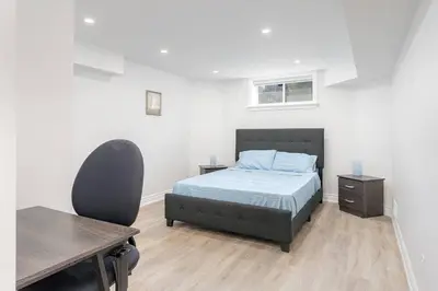 a bedroom with a bed and a desk and a chair at Cozy 1BR Lower Level Walking distance to shops in Richmond Hill