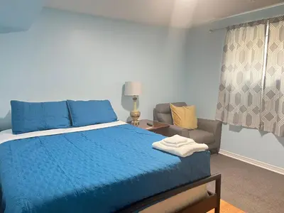 a bedroom with a blue bed and a chair at Renaissance Guest House in Oshawa