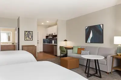 a hotel room with two beds and a couch at Staybridge Suites Aurora East by IHG in Aurora