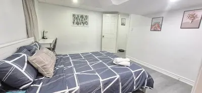 a bedroom with a bed with a blue and white comforter at Pacific Mall Bright & Cozy Rooms with Privated Bathrooms in Toronto