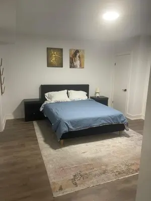 a bedroom with a bed with a blue blanket and a rug at Self contained lower level 1 Bedroom apartment in Oshawa