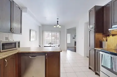 a kitchen with wooden cabinets and a microwave at Charming 4-bed Home Away From Home in Brampton, ON in Brampton