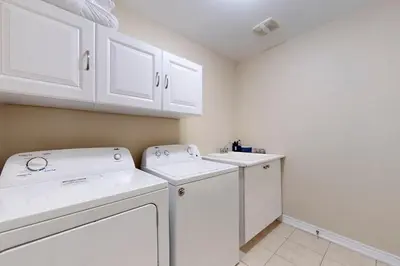 a laundry room with white cabinets and a washer and dryer at Charming 4-bed Home Away From Home in Brampton, ON in Brampton