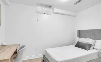 a white bedroom with a bed and a wooden table at Stylish Modern 2-bedroom Basement Suite in Brampton