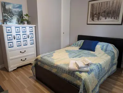 a bedroom with a bed with a dresser and two towels at Cozy home away from home, close to hospital, college, and university with free parking in Peterborough