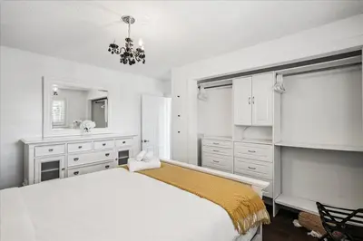 a white bedroom with a bed and a chandelier at Bright 3-BDRM House, Family Home & Parking, YYZ Airport in Mississauga