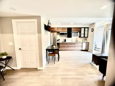 a living room with a table and a kitchen at The Simple Escape, Walkout Basement on Ravine in Kitchener