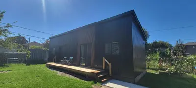 a black tiny house with a wooden deck at Bright Garden Suite 1 Bedroom and Den in Toronto