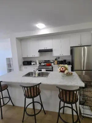 a kitchen with a counter with chairs and a sink at Modern Stylish Cozy Home Balcony Wifi in Caledonia