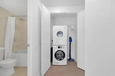 a bathroom with a washing machine and a toilet at Prime 2BR Condo with Massive Patio & Parking in Toronto