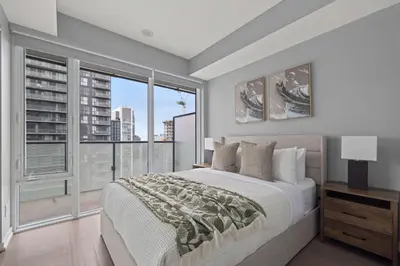 a bedroom with a large bed and a large window at Chic 1-Bedroom Downtown Toronto Getaway in Toronto