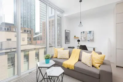 a living room with a couch and a large window at Chic 1BR King Suite TOs Entertainment District in Toronto