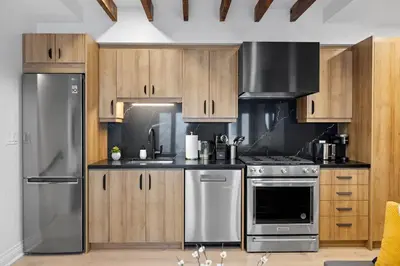 a kitchen with wooden cabinets and stainless steel appliances at Modern Parkdale Getaway 1-Bedroom Parking in Toronto