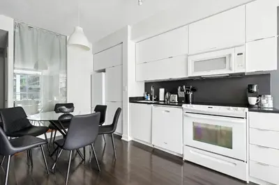 a kitchen with white cabinets and a table and chairs at Gorgeous 2BR in Downtown Toronto w City Views in Toronto