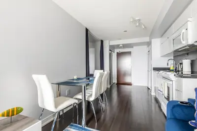 a kitchen and dining room with a table and white chairs at Spacious 1 Bedroom plus Den Condo Iceboat Terrace Downtown Toronto in Toronto