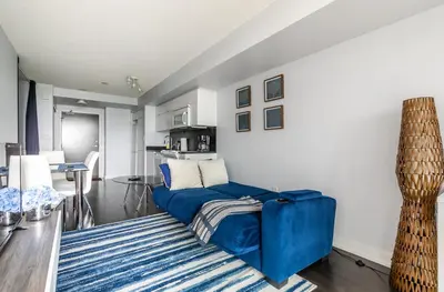 a living room with a blue couch and a table at Spacious 1 Bedroom plus Den Condo Iceboat Terrace Downtown Toronto in Toronto