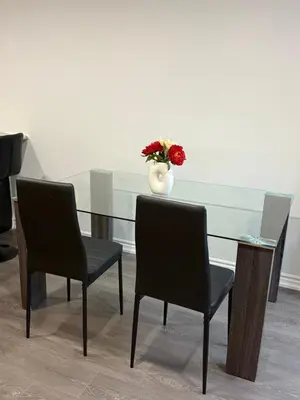 a glass table with two chairs and a vase with red flowers at Comfy Basement Suite in Quiet Neighbourhood in Whitby