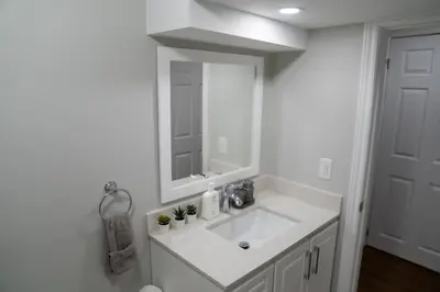 a white bathroom with a sink and a mirror at Studio Apartment B - Full Kitchen - Cozy and Modern in Brampton