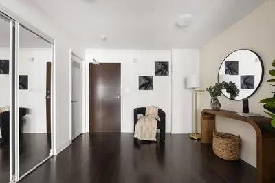 a living room with a mirror and a chair at Stylish 1BR Condo with Patio Steps from Waterfront in Toronto