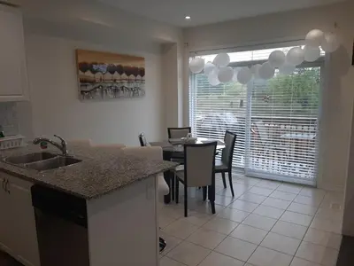 a kitchen with a sink and a table with chairs at Modern 5-bedroom house close to Ardagh Bluffs in Barrie