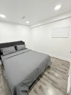 a white room with a large bed in it at Modern & cozy one Bedroom Basement Suite with Kitchen and parking- sleeps 4 in Mississauga