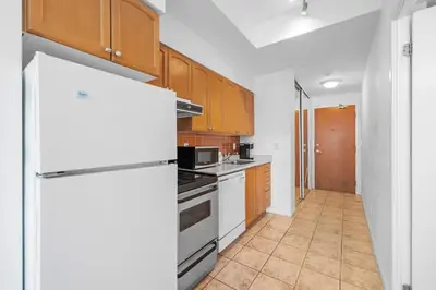 a kitchen with a white refrigerator and wooden cabinets at Chic Fort York Studio Cozy Retreat in Downtown TO in Toronto