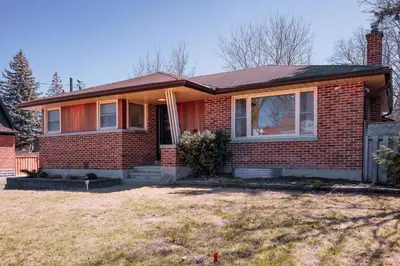 a red brick house with a window and a fence at Stylish, Spacious 6-Bedroom Home in the GTA in Whitby