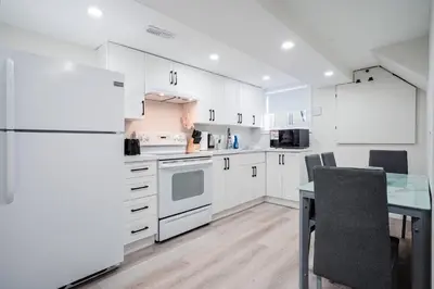 a kitchen with white cabinets and a table and a refrigerator at Bright & Cozy Home in the GTA (Basement Apartment) in Whitby