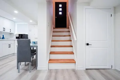 a staircase in a kitchen with a table and a door at Bright & Cozy Home in the GTA (Basement Apartment) in Whitby