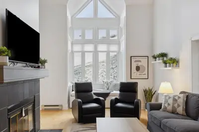 a living room with a couch and chairs and a tv at Slopeside Ski In Ski Out Second Floor Condo in Blue Mountains