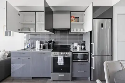 a kitchen with stainless steel appliances and gray cabinets at Bright 2BR Downtown Toronto Condo in Toronto