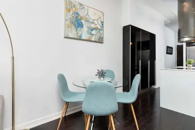 a dining room with a glass table and blue chairs at Glamorous City Escape King Bed & CN Tower Views in Toronto