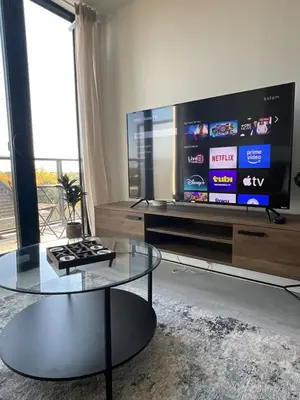a living room with a tv and a glass coffee table at New Condo With Large Balcony - The Queensway Retreat in Toronto