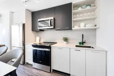 a kitchen with white cabinets and a black stove top oven at Skyline Escape • 3BR Penthouse with Terrace in Toronto